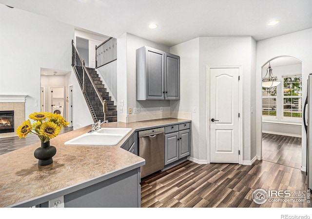 kitchen with a fireplace, dark hardwood / wood-style floors, gray cabinetry, and dishwasher