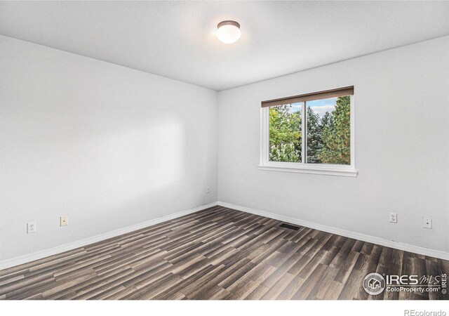 spare room with dark wood-type flooring