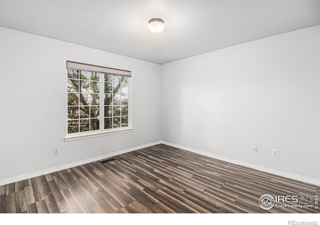 unfurnished room with dark hardwood / wood-style flooring