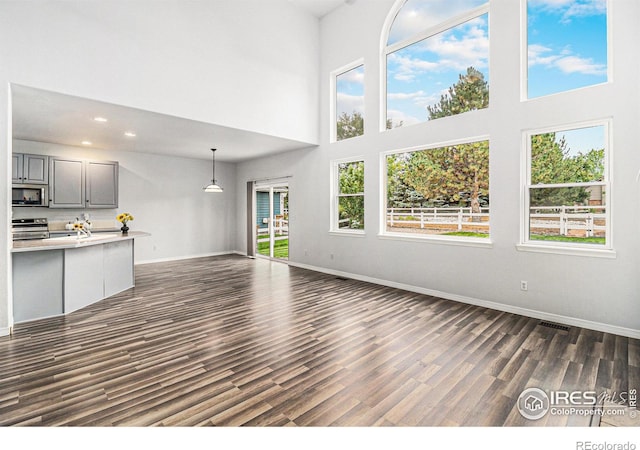 unfurnished living room featuring a high ceiling and dark hardwood / wood-style flooring