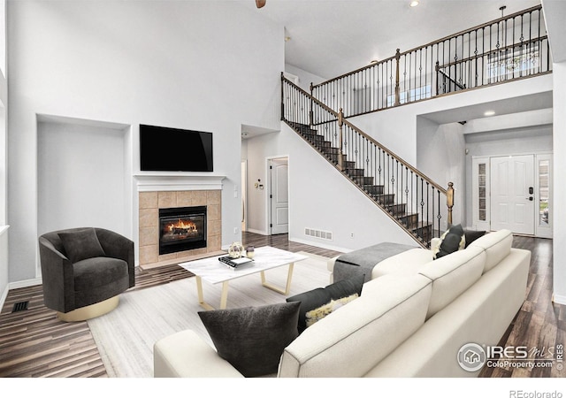 living room featuring hardwood / wood-style flooring, a high ceiling, and a fireplace