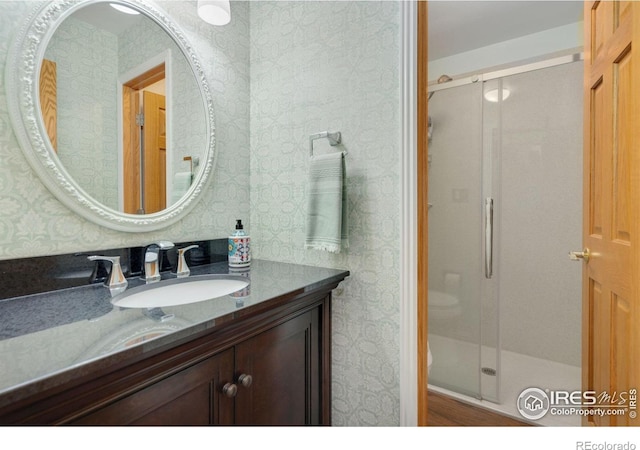 bathroom featuring a shower with door and vanity