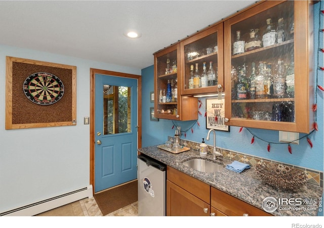 kitchen featuring dark stone countertops, dishwasher, baseboard heating, and sink