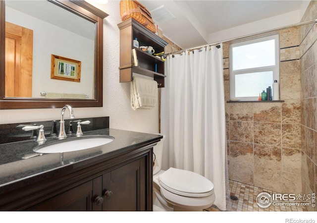 bathroom with walk in shower, vanity, and toilet