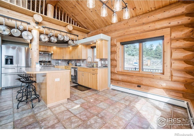 kitchen with rustic walls, stainless steel appliances, sink, decorative light fixtures, and a kitchen island