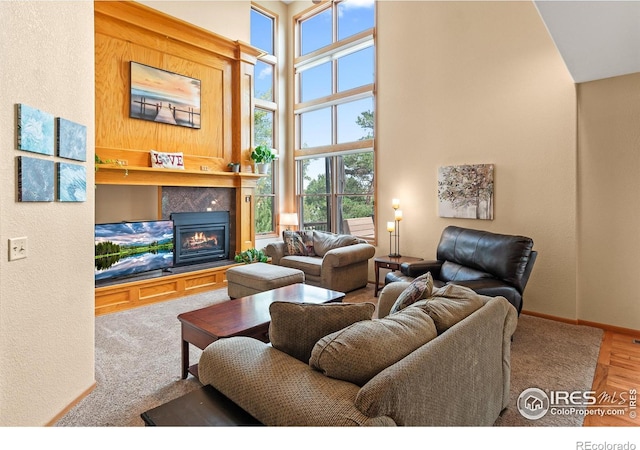 living room featuring a fireplace, plenty of natural light, wood-type flooring, and a high ceiling