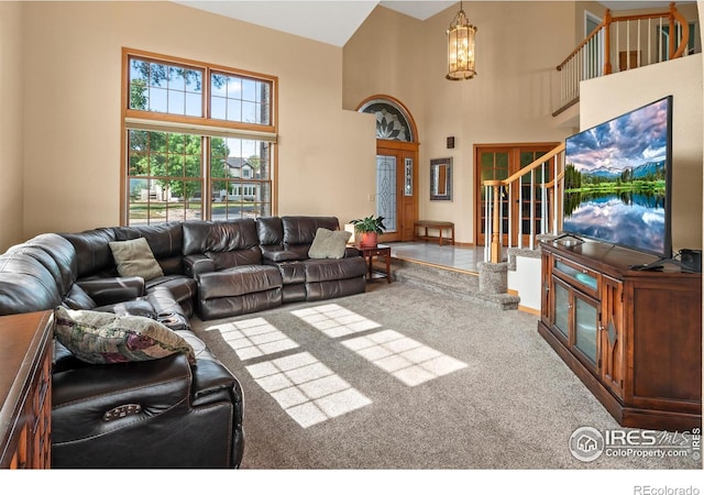 living room featuring carpet, a towering ceiling, and a notable chandelier