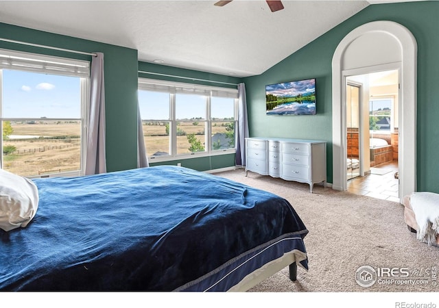 carpeted bedroom featuring lofted ceiling, a rural view, and ceiling fan