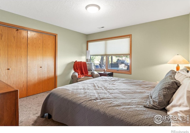 bedroom featuring a closet, light carpet, and a textured ceiling