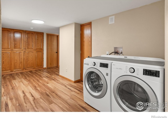 washroom with light hardwood / wood-style flooring, washer and clothes dryer, and cabinets