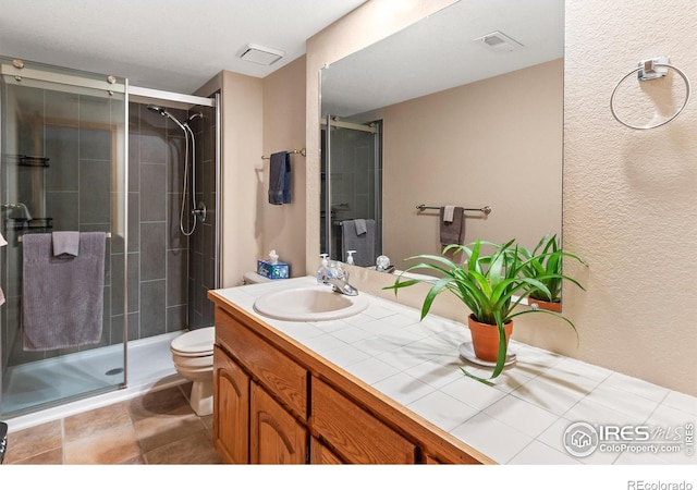 bathroom with vanity, a shower with shower door, and toilet