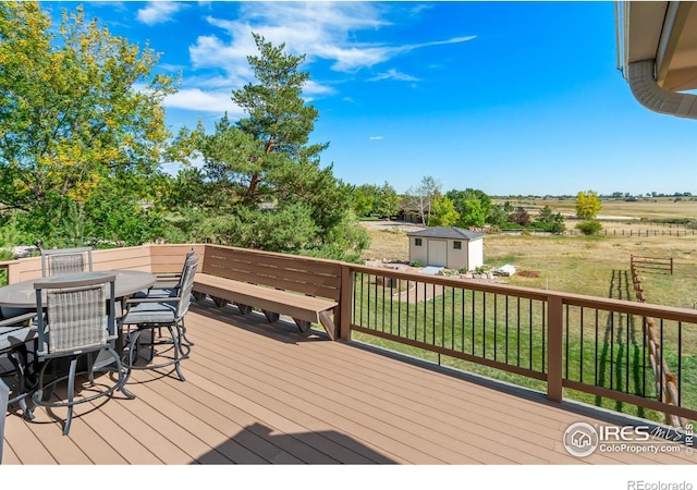 wooden deck featuring a storage unit, a yard, and a rural view