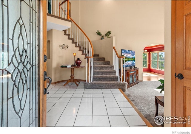 foyer entrance with light tile patterned floors and a high ceiling