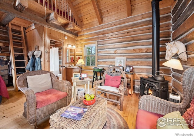 living room featuring a wood stove, wooden ceiling, high vaulted ceiling, rustic walls, and beam ceiling