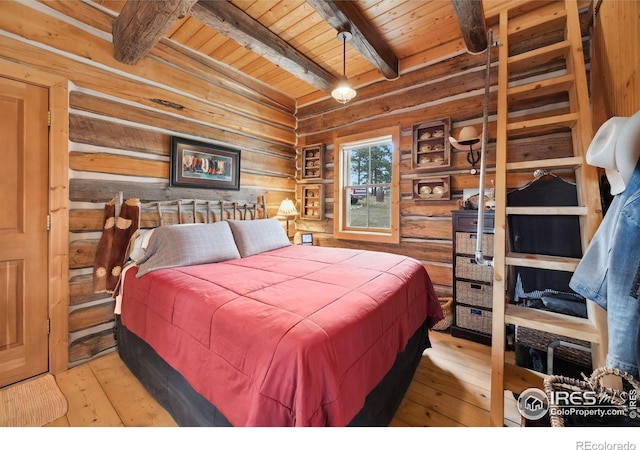 bedroom with wood walls, beamed ceiling, wood ceiling, and light wood-type flooring