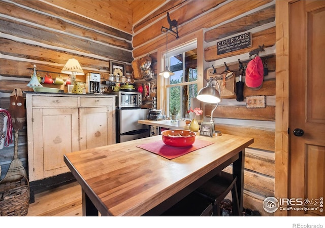 kitchen featuring wood walls, stainless steel appliances, and hanging light fixtures