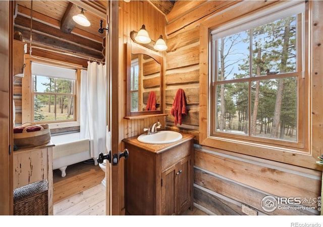 bathroom with beam ceiling, wood walls, hardwood / wood-style floors, vanity, and wood ceiling