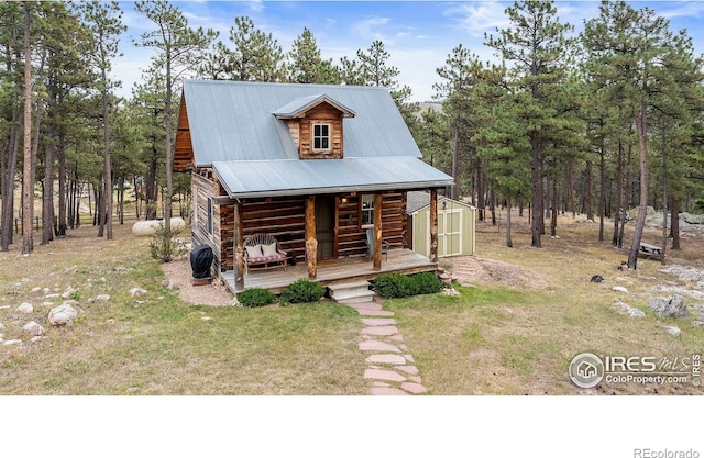 cabin featuring covered porch, a storage shed, and a front yard