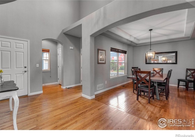 dining room featuring wood-type flooring and a raised ceiling