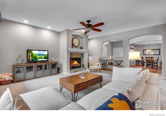 carpeted living room with ceiling fan with notable chandelier