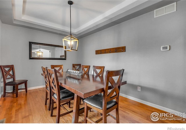 dining area featuring light wood-type flooring and a tray ceiling