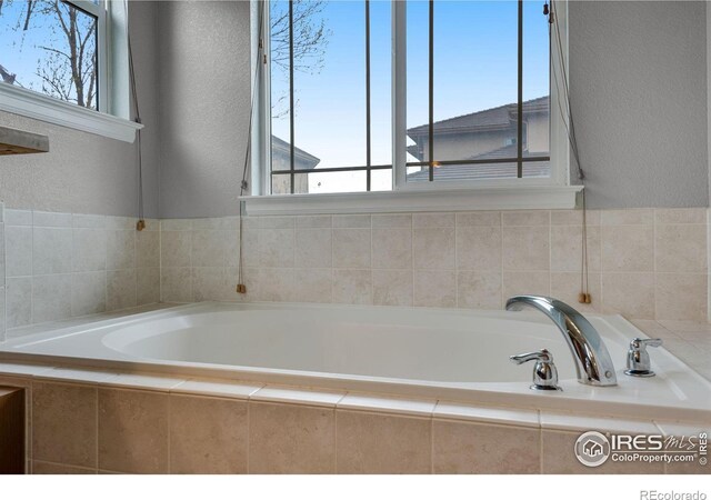 bathroom with a healthy amount of sunlight and a relaxing tiled tub