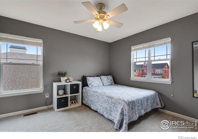 carpeted bedroom with multiple windows and ceiling fan