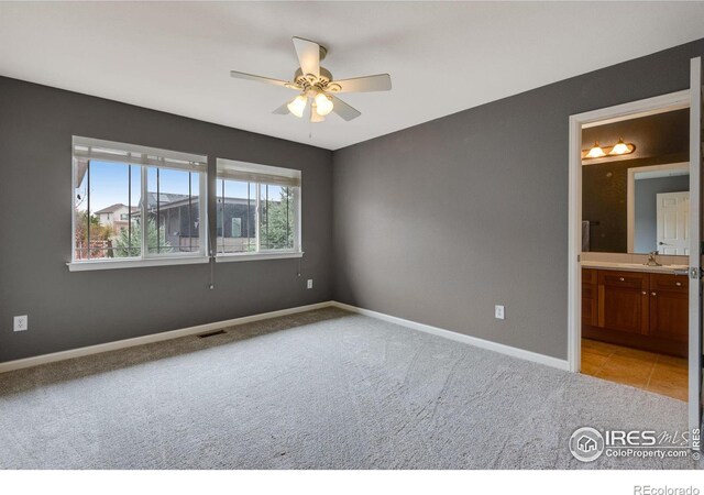 unfurnished bedroom with light colored carpet, ceiling fan, and ensuite bathroom