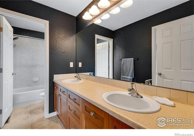 full bathroom featuring tiled shower / bath combo, vanity, tile patterned flooring, and toilet