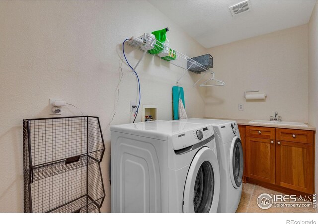 laundry room with cabinets, a textured ceiling, separate washer and dryer, and sink