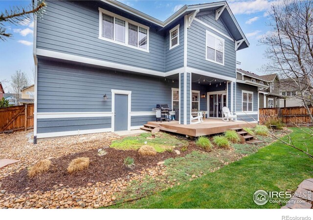 back of property featuring a wooden deck and a lawn