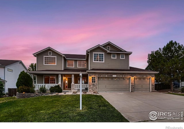 view of front of property with covered porch, a garage, and a lawn