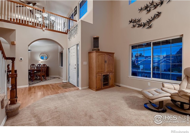 carpeted entryway with a towering ceiling and a notable chandelier