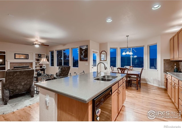 kitchen with a center island with sink, ceiling fan with notable chandelier, sink, black dishwasher, and decorative light fixtures