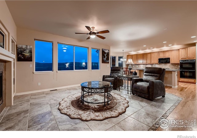 living room featuring a tile fireplace and ceiling fan