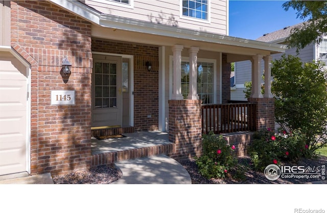 entrance to property featuring covered porch and a garage