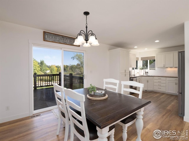 dining space with plenty of natural light, sink, a chandelier, and hardwood / wood-style flooring