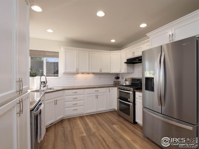 kitchen featuring appliances with stainless steel finishes, light wood-type flooring, white cabinetry, and sink