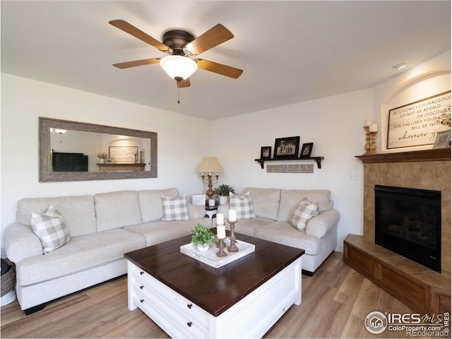 living room featuring light hardwood / wood-style floors, a fireplace, and ceiling fan