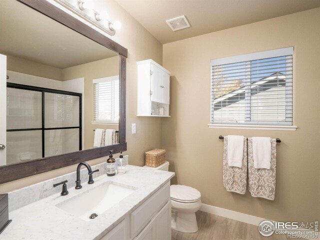 bathroom featuring vanity, hardwood / wood-style floors, toilet, and an enclosed shower