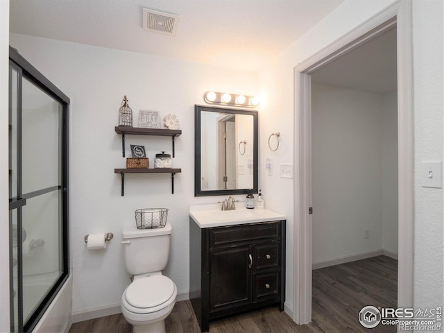 full bathroom with wood-type flooring, shower / bath combination with glass door, vanity, and toilet