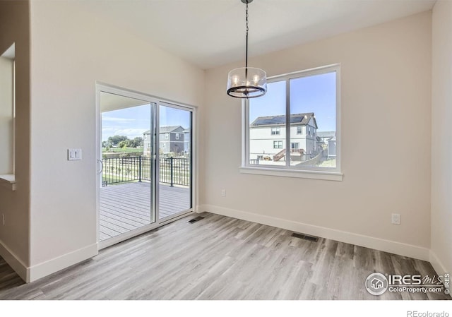 unfurnished dining area featuring a notable chandelier, light hardwood / wood-style floors, and a healthy amount of sunlight