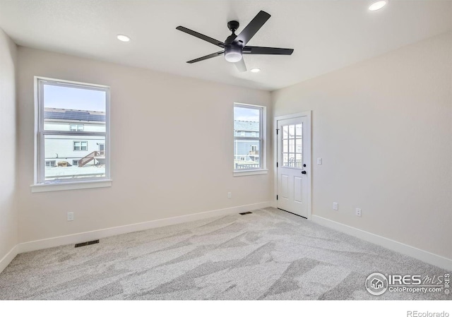 carpeted empty room featuring ceiling fan and plenty of natural light