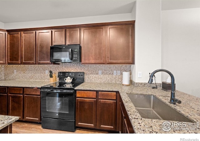 kitchen featuring light stone counters, sink, tasteful backsplash, light hardwood / wood-style flooring, and black appliances