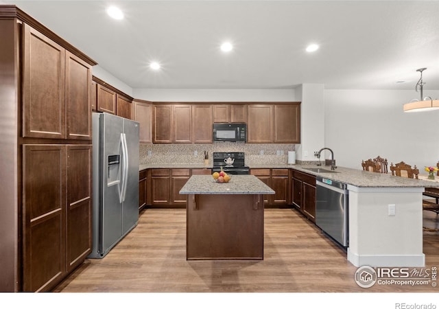 kitchen with sink, light wood-type flooring, kitchen peninsula, and black appliances