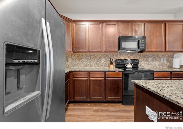 kitchen with light stone countertops, light hardwood / wood-style flooring, backsplash, and black appliances