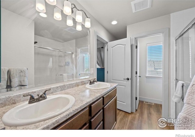 bathroom featuring wood-type flooring, a shower with shower door, and vanity