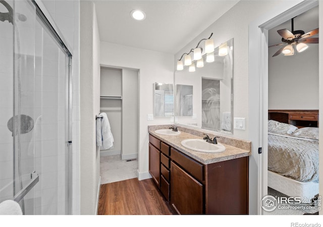 bathroom with ceiling fan, vanity, a shower with shower door, and hardwood / wood-style floors