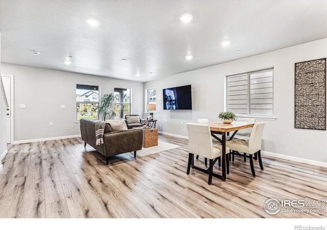 dining space featuring light wood-type flooring and a textured ceiling