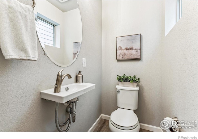 bathroom with wood finished floors, toilet, baseboards, and a sink